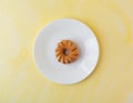 Glazed cruller on a plate atop a yellow background Royalty Free Stock Photo