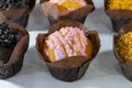 Glazed cupcakes. Cupcakes in craft paper wrapper on a white counter. Various sprinkles with colored crumbs. Sale of