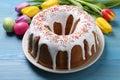 Glazed Easter cake with sprinkles, painted eggs and tulips on blue wooden table, closeup Royalty Free Stock Photo