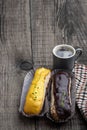 Glazed eclairs with a cup of coffee on wooden table Royalty Free Stock Photo