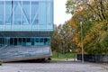 Glazed facade of a building with a sloping car ramp and an avenue of trees next to it on an autumn day