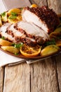 Glazed roast pork with potatoes, oranges and apples close-up. Vertical