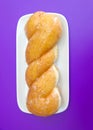 Glazed twist donut on rectangle plate on purple background Royalty Free Stock Photo