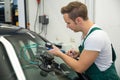 Glazier repairing stone-chipping damage on car's windshield Royalty Free Stock Photo