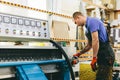 Glazier worker operates glass cutting machine in workshop