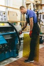 Glazier worker operates glass cutting machine in workshop