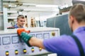 Glazier worker operates mirror glass cutting machine in workshop