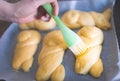 Glazing braided sweet yeast buns using silicone pastry brush before baking