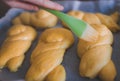 Glazing braided sweet yeast bunns using silicone pastry brush before baking