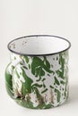 A gleaming cup with white and green patterns, now used to savor beverages with a vintage classic touch.