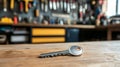 Gleaming silver key on rustic wooden counter in workshop setting with organized tools and key racks in the background