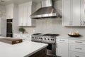 gleaming stainless steel range hood and sleek countertops in modern white kitchen Royalty Free Stock Photo