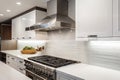 gleaming stainless steel range hood and sleek countertops in modern white kitchen Royalty Free Stock Photo