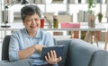 Gleeful Asian female using tablet at home