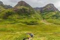 GLENCOE, SCOTLAND - AUGUST 16 2023 - Hikers in the green, dramatic valley of Glen Coe under a moody grey sky Royalty Free Stock Photo