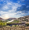 Glenfinnan Railway Viaduct in Scotland with the Jacobite steam train against sunset over lake Royalty Free Stock Photo