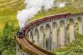 GLENFINNAN, SCOTLAND - AUGUST 16 2023 - Famous steam training passing over a curved viaduct at Glenfinnan in the Scottish