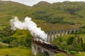 GLENFINNAN, SCOTLAND - SEPTEMBER 3 2021: Crowds of people gather to watch the traditional Jacobite Steam Train crossing the famous