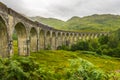 Glenfinnan Viaduct from side on cloudy day with passing train