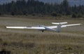 Glider ultralight plane flying near mountains, landing on earth aerodrome