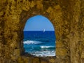 A glimpse of the Mediterranean framed by an opening in the sea wall of Chania harbour, Crete on a bright sunny day Royalty Free Stock Photo