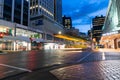 Glistening streets and light streams of passing traffic in city downtown business district with illuminated business brands and
