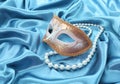 Glitter gold mask and pearl necklace on turquoise silk drape Royalty Free Stock Photo