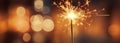 Glittering burning sparkler against blurred colorful bokeh background. Celebrating Christmas and New Year\'s Eve