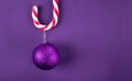 Glittering purple bauble hanging on candy cane