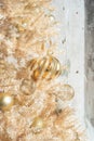 Glittery gold Christmas ornaments on a gold artificial tree - vertical