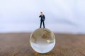 Global and Business Concept. Businessman miniature people figure standing on glass clear world ball model Royalty Free Stock Photo