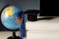 Global education concept. Graduation hat on books and globe Royalty Free Stock Photo