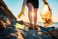 Global environmental pollution. A volunteer collects plastic bottles on the ocean shore. Legs close-up. Cleaning of the Royalty Free Stock Photo