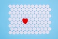 Global healthcare concept. Little red heart. Background of white pills macro with a red heart lying on a blue background