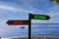 Global or local symbol. Concept word Global or Local on beautiful signpost with two arrows. Beautiful blue sea sky with clouds Royalty Free Stock Photo