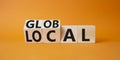 Global and Local symbol. Turned wooden cubes with words Global and Local. Beautiful orange background. Business and Global and