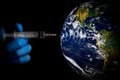 global pandemic - hand with syringe injecting vaccine into the planet earth