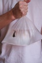 A man holds a fish in a plastic bag close-up