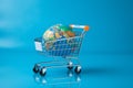 Global shopping Trolley on blue globe surface symbolizes worldwide retail accessibility.