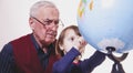 Global travel and geography concept. Portrait of happy grandfather and granddaughter looking at globe and planning travel Royalty Free Stock Photo