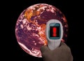 Global warming conceptual image. Hand with infrared thermometer measuring temperature of the planet Earth. Threat for life of the