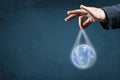 Globalization, Energy and ecology concept. man`s hand in suit holds the planet earth by the strings. blue background, copy space Royalty Free Stock Photo