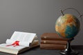 Globe, books and diploma with red