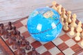 Globe and chess pieces on both sides Royalty Free Stock Photo