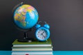 The globe and clock stand on a stack of books, on a blue table