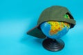 Globe with a green baseball cap on it on a blue background