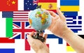 Globe in hands on a background of flags from around the world Royalty Free Stock Photo