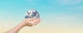 Globe in hands over blue sky background. Save of earth. Royalty Free Stock Photo