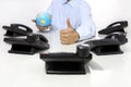 Globe and like hand with office phones on desk, global internati Royalty Free Stock Photo