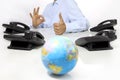 Globe and like hand with office phones on desk, global internati Royalty Free Stock Photo